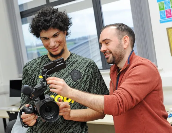 Media student looking at camera with tutor  (Graphics thumbnail image)