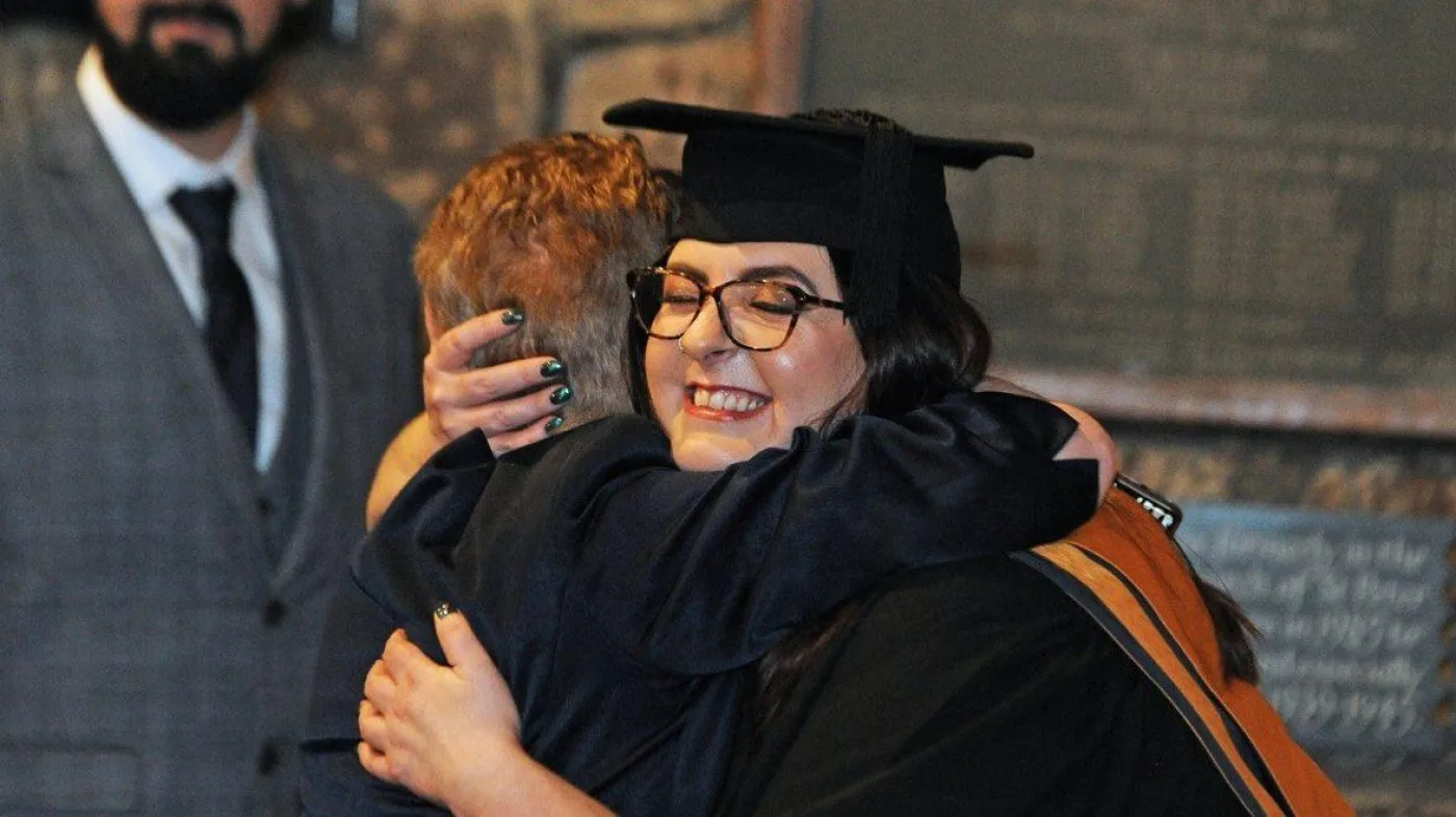 Graduate hugging family member